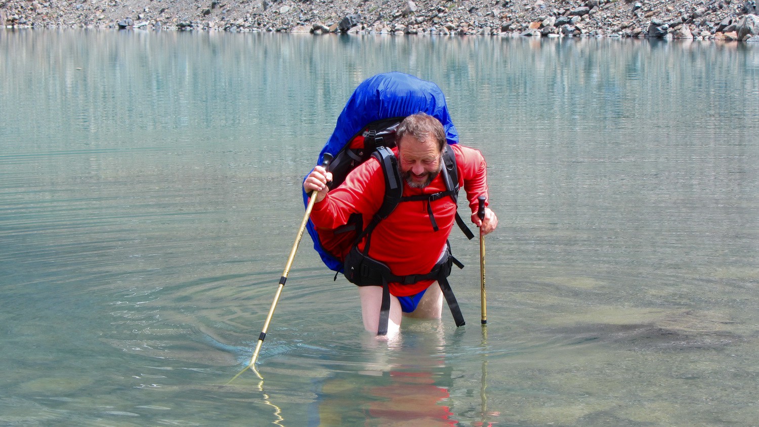 Tommy is carrying a heavy backpack in the deep water